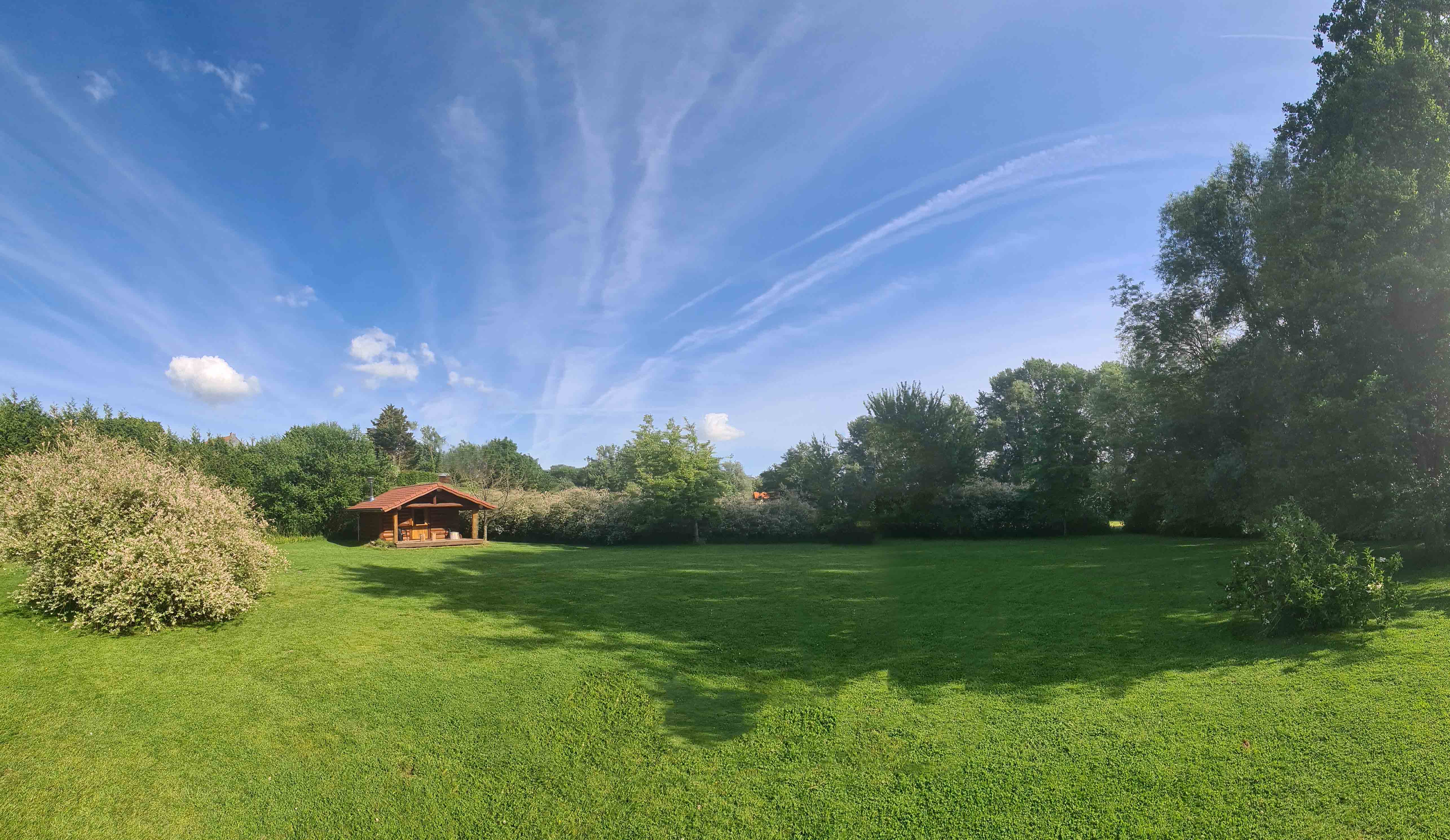 Chalet en bois avec terrasse couverte au fond du jardin